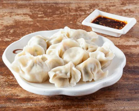 Une portion de raviolis bouillis, pâte translucide, dans un plat en porcelaine