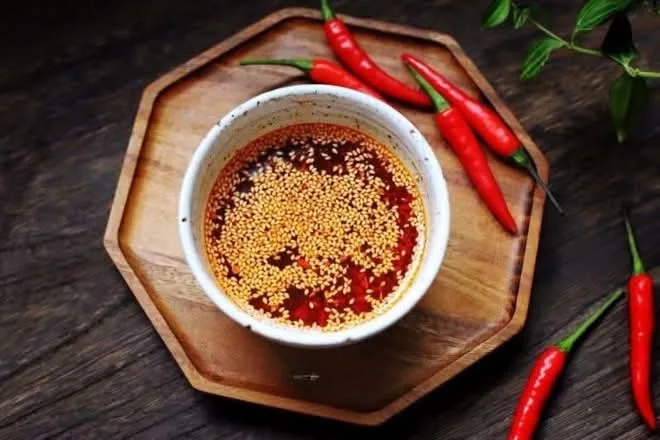 La sauce piquante maison dans un bol en bois, entourée de piments frais