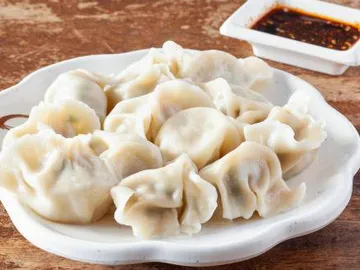 Douze raviolis bouillis à la pâte translucide, dans un plat en porcelaine